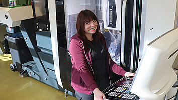 Industriemeisterin Michelle Schulz steht an der 5-Achs-Bearbeitungsmaschine in der FBH-Werkstatt