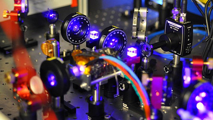 Complex arrangement of optical devices on a laboratory plate. Several lenses and cameras are arranged in different positions and connected with colorful cables.