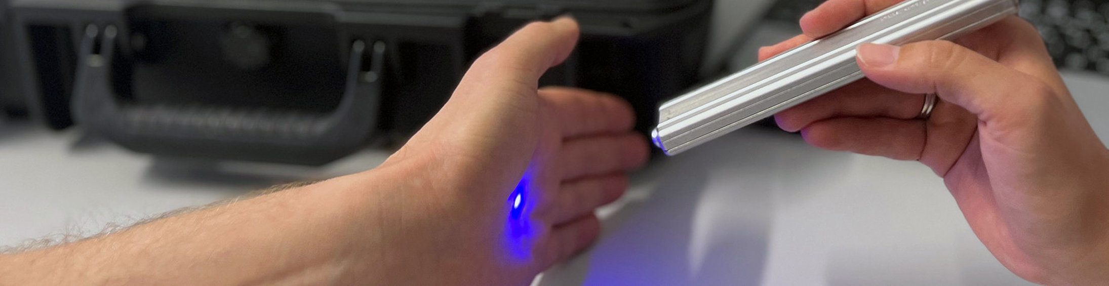 A palm is scanned with the Raman system sensor. The Raman system (a suitcase and a laptop) can be seen in the background.