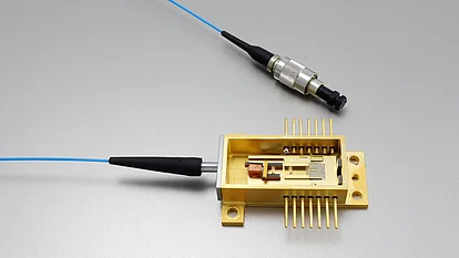 Golden modular laser diode on a base plate, connected to a blue optical fibre. The waveguide and a connected plug component are also visible.