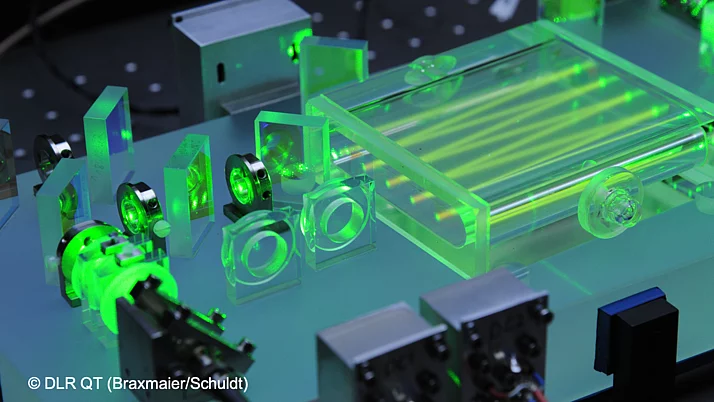 Technical arrangement with transparent and green components, including optical elements and a rectangular container. The devices are arranged on a work surface.