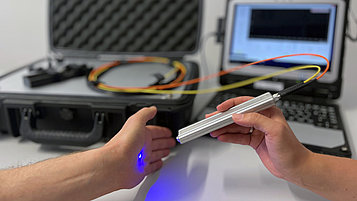 A palm is scanned with the Raman system sensor. The Raman system (a suitcase and a laptop) can be seen in the background.