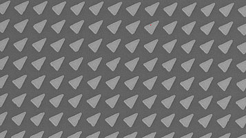 Microscopic image of a photonic crystal lattice with a repeating triangular pattern on a semiconductor surface.
