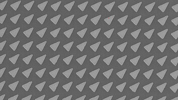 Microscopic image of a photonic crystal lattice with a repeating triangular pattern on a semiconductor surface.