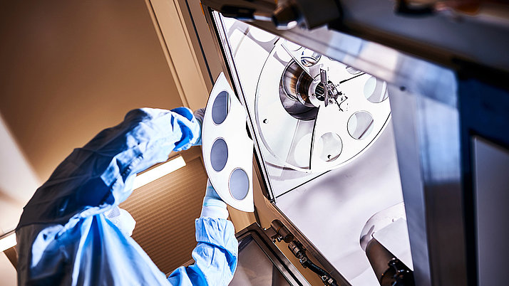 View from below of a person in the clean room inserting a wafer into the system for coating.