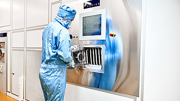 Image showing a person loading the sputter tool with wafers clamped on carriers.