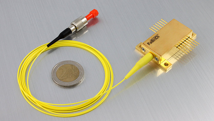 Lasermodul mit Faserkopplung sowie eine 2 Euromünze zum Größenvergleich.