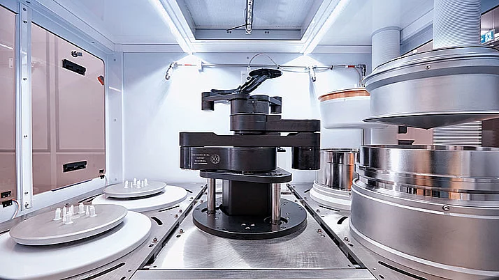 Modern production machine. At the center is a rotating arm surrounded by several large silver cylinder parts.