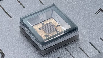 Makroaufnahme einer Fern-UV-LED in einem transparenten Gehäuse auf einem metallischen Lineal, das als Maßstab dient. 