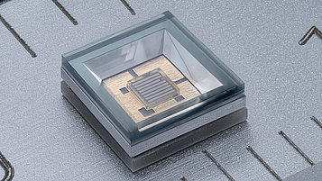 Makroaufnahme einer Fern-UV-LED in einem transparenten Gehäuse auf einem metallischen Lineal, das als Maßstab dient. 