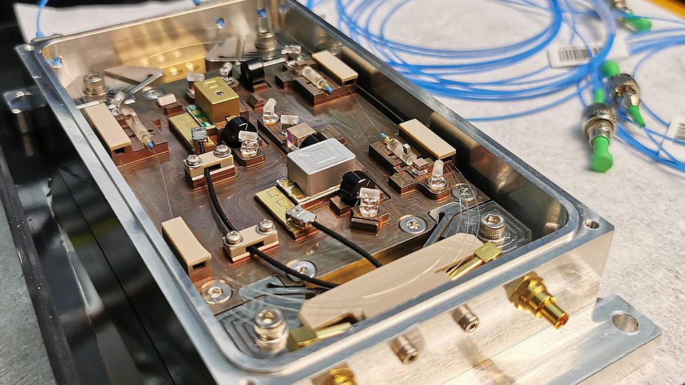 Geöffnetes Gehäuse mit elektronischen Komponenten. Darin befinden sich Platinen, Kabel, Schalter und verschiedene Bauteile, die miteinander verbunden sind.