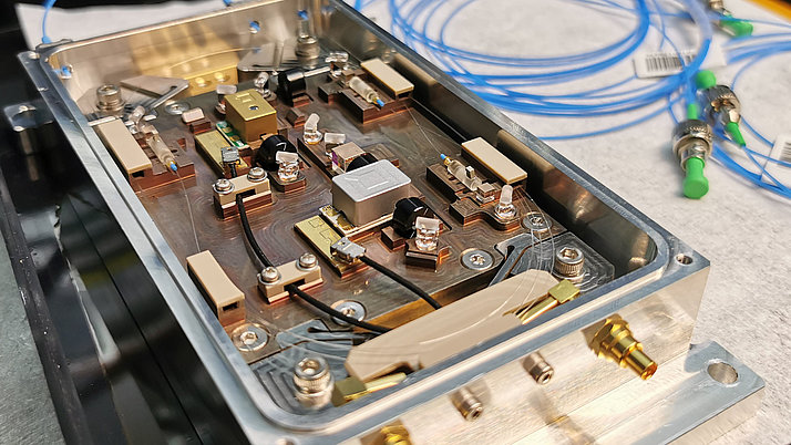 Geöffnetes Gehäuse mit elektronischen Komponenten. Darin befinden sich Platinen, Kabel, Schalter und verschiedene Bauteile, die miteinander verbunden sind.