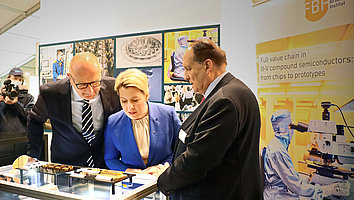 Dietmar Woidke und Franziska Giffey beugen sich über Lasermodule für Weltraumanwendungen beim Presserundgang auf der ILA 2022. FBH-Direktor Günther Tränkle erläuert deren Funktion.