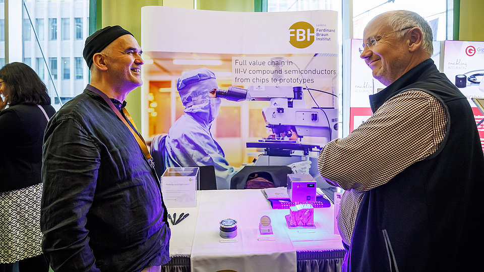 Zwei Männer unterhalten sich vor einem Messestand.