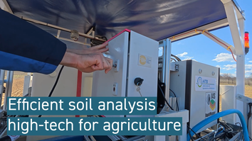 Ein Mann aktiviert ein modernes Gerät zur Bodenauswertung. Das Gerät ist mit einem Etikett des ATB (Leibniz-Institut für Agrartechnologie) gekennzeichnet. Im Hintergrund ist eine landwirtschaftliche Landschaft sichtbar. Der Fokus liegt auf der hochmodernen Technologie für die Landwirtschaft.