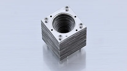 Photograph of an assembled corrugated horn made from stacked square metal plates fastened with four screws, with a tapered circular opening at the center.