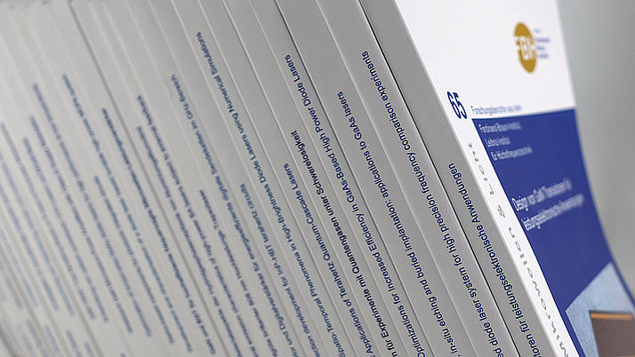 A series of portrait-format brochures is arranged upright. The covers show titles and information on various topics.