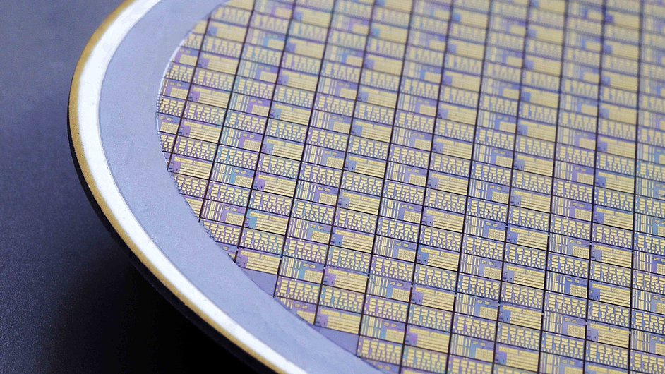 Silicon wafer covered with a pattern of intricate, colorful designs. The wafer is partially visible, with a metallic edge surrounding it.
