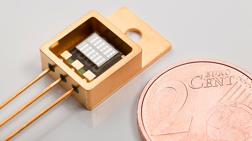 Flip-chip montierten GaN-Leistungstransistor neben dem als Größenvergleich ein Cent-Stück liegt