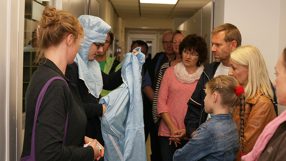 Guided tour at parents on tour with parents and children standing in front of the cleanroom