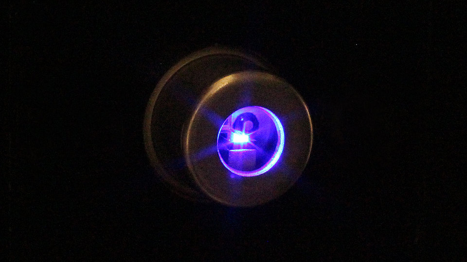 Laserquelle, aus der ein blau-violetter Laserstrahl austritt
