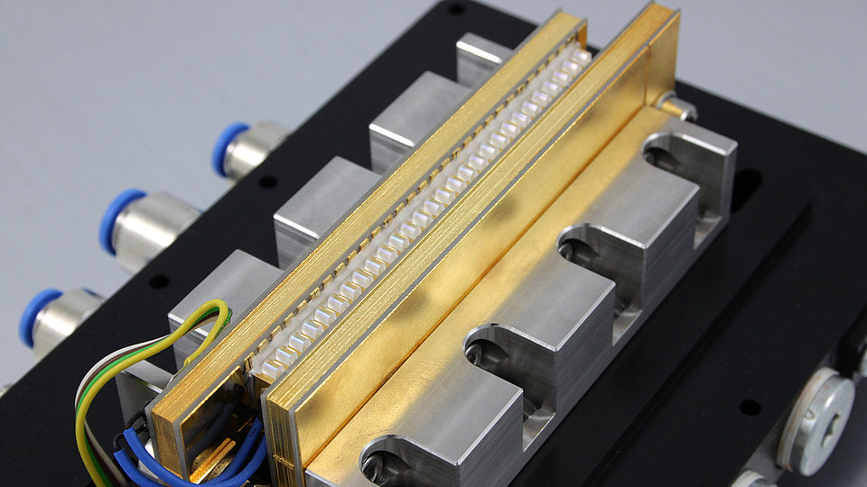 Fig. 1: Picture showing ready-for-shipment stack module comprising 24 lasers, each equipped with its own individual fast axis collimation (FAC) lens. Common slow axis collimation (SAC) not shown.