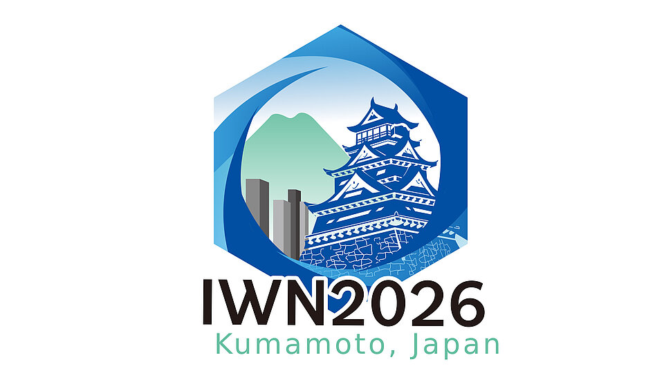 Logo for IWN 2026 featuring a stylized depiction of Kumamoto Castle within a hexagonal shape, with mountains and water elements in blue. Text below reads "IWN2026" and "Kumamoto, Japan.