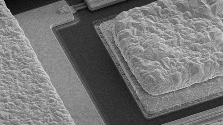Mikroskopische Ansicht von strukturierten Oberflächen auf einem Chip. Die Bilddetails zeigen unregelmäßige, erhabene und flache Bereiche.