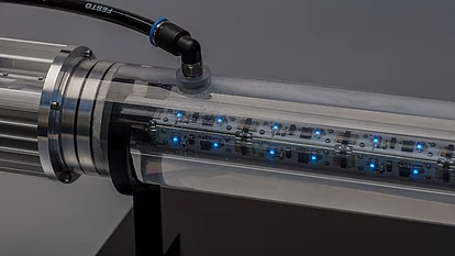 Transparenter Zylinder mit eingebauten, blauen LED-Leuchten und elektronischen Komponenten. An einem Ende des Zylinders ist ein Verbindungselement zu sehen. 