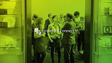 Einige Menschen in Bürokleidung stehen in einem Raum und unterhalten sich in kleinen Grüppchen. Darauf der Schriftzug "green ict.connect²³"