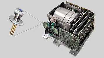 Close-up of a QYRO Gyroscope, focusing on one of the VCSELs used in its operation. The image shows the circular VCSEL sensor with gold pins, connected to the gyroscope's circuit boards and internal components.
