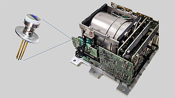 Close-up of a QYRO Gyroscope, focusing on one of the VCSELs used in its operation. The image shows the circular VCSEL sensor with gold pins, connected to the gyroscope's circuit boards and internal components.