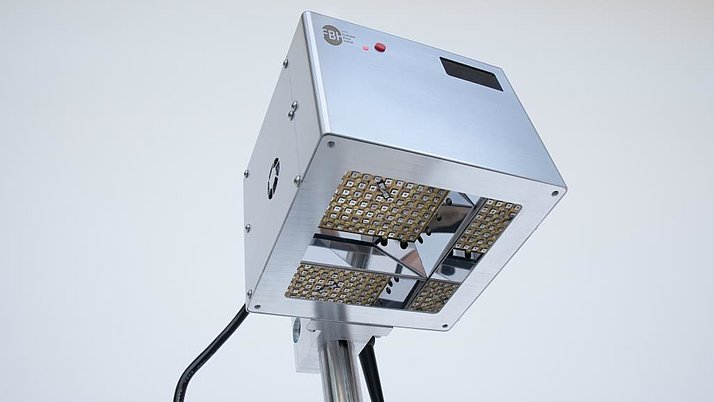 An LED lamp with a square, silver housing. The underside features several small LED lights, while a display and control buttons are visible at the top.