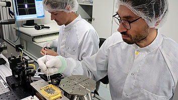 Auf dem Foto sind zwei Mitarbeiter zu sehen, die in einem Labor an einem Diodenlasermodul arbeiten.