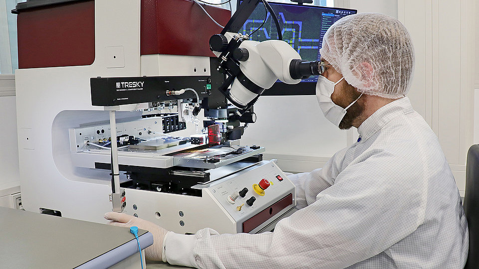 Photo of a male technician in a lab coat using a pick-and-flip station. 