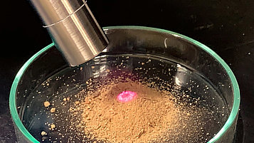 Picture showing raman probe illuminating soil sample in Petri dish. 