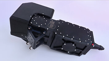 Schwarzes, mechanisches Gerät mit einem rechteckigen Oberteil und einer zylindrischen Auslassöffnung. Es ist mit Schrauben und einem beschrifteten Bereich versehen.