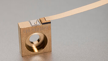 A Distributed Feedback (DFB) laser mounted on a C-Mount. The compact setup features a metallic block with an integrated laser diode, connected to a thin wire for electrical connection.