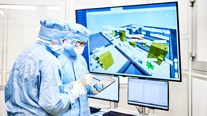 Two female employees in a clean room suit in front of a display