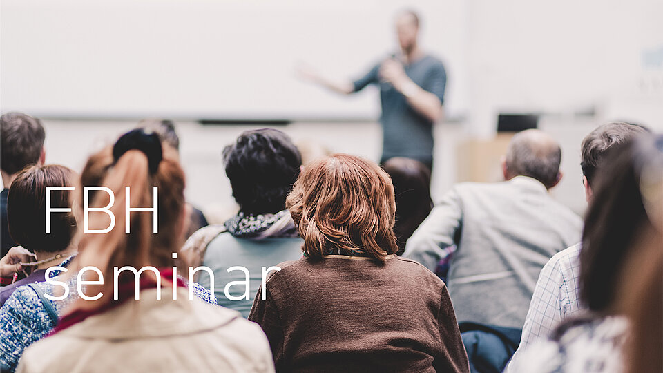 Publikum blickt auf einen unscharfen Vortragenden, der vorne in einem Raum spricht, mit eingeblendetem Text „FBH Seminar“.